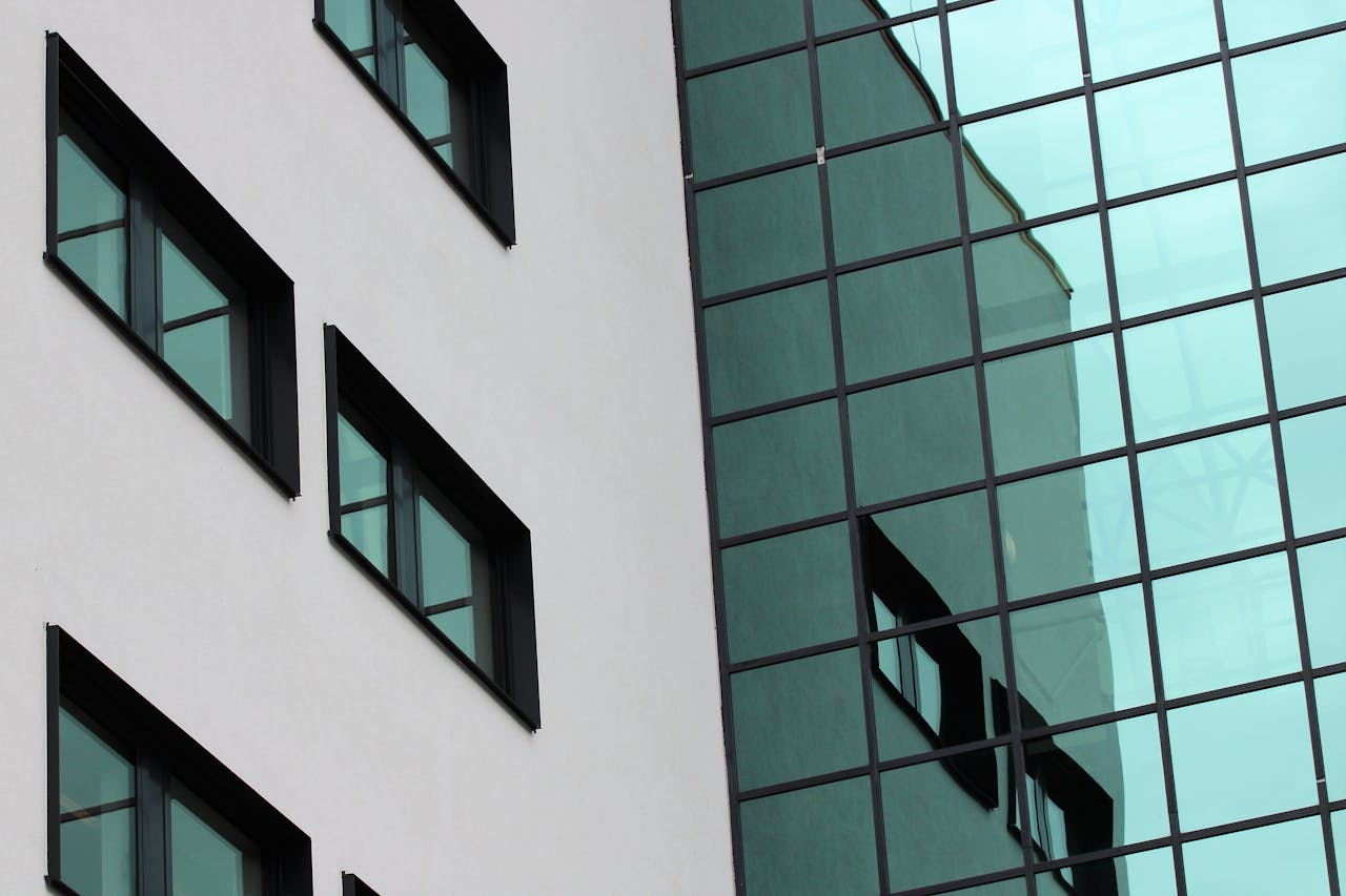 Close-up of a modern building facade with glass windows reflecting the urban environment.