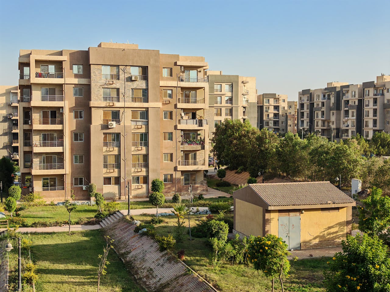 Aerial view of a modern apartment complex with lush greenery on a sunny day.